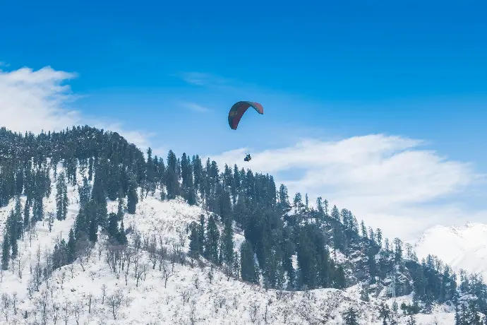 Paragliders flying over snowy Solang Valley near Manali - Mountain Junkey