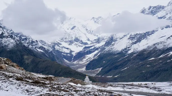 Highway winding through snow at Rohtang Pass - Mountain Junkey