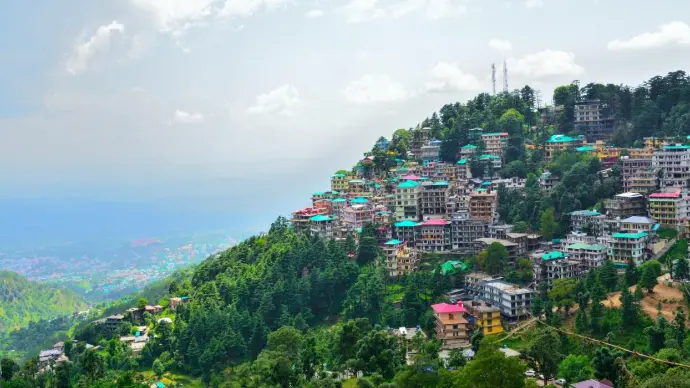 Hillside rooftops of McLeodganj with Dhauladhar range view – Mountain Junkey