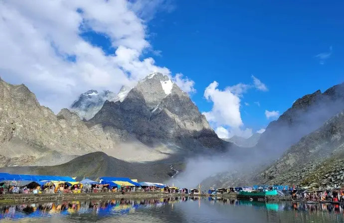 Mirror-like reflection of Himalayan peaks in serene Manimahesh Lake, one of Panch Kailash pilgrimage spots - Mountain Junkey