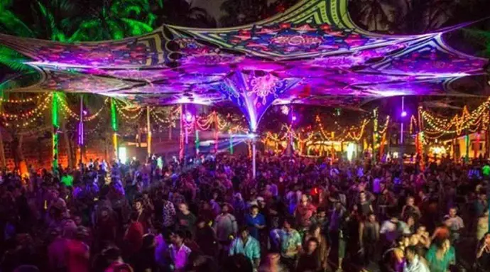 Outdoor Goa beach club party at night with dancing crowd - Mountain Junkey