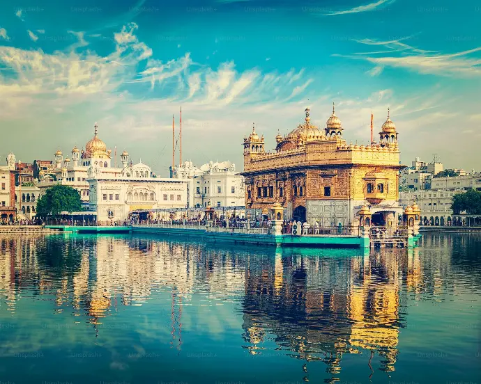 Illuminated Golden Temple at night with reflections in water - Mountain Junkey